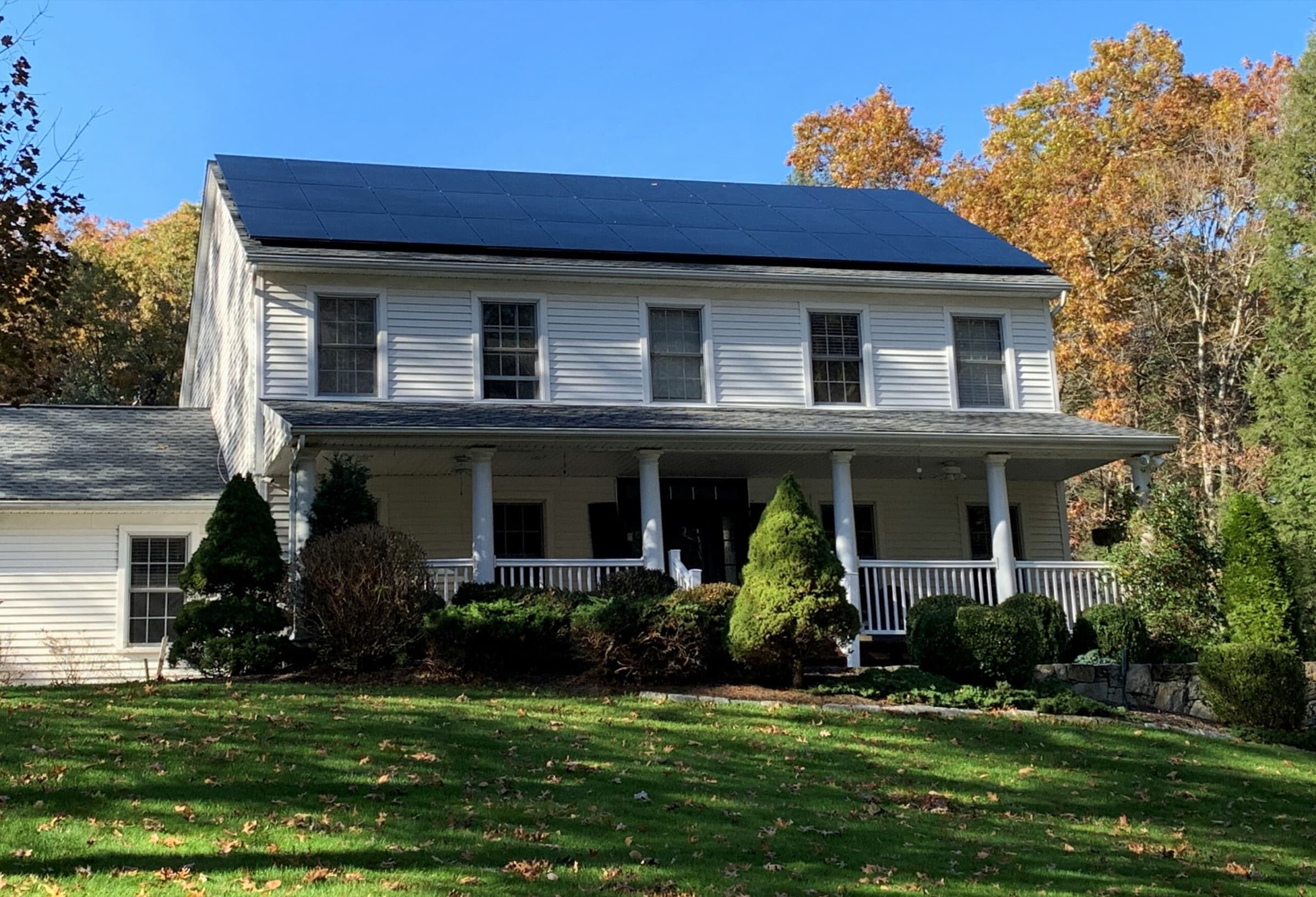 Two-story white home with solar panels on the roof
